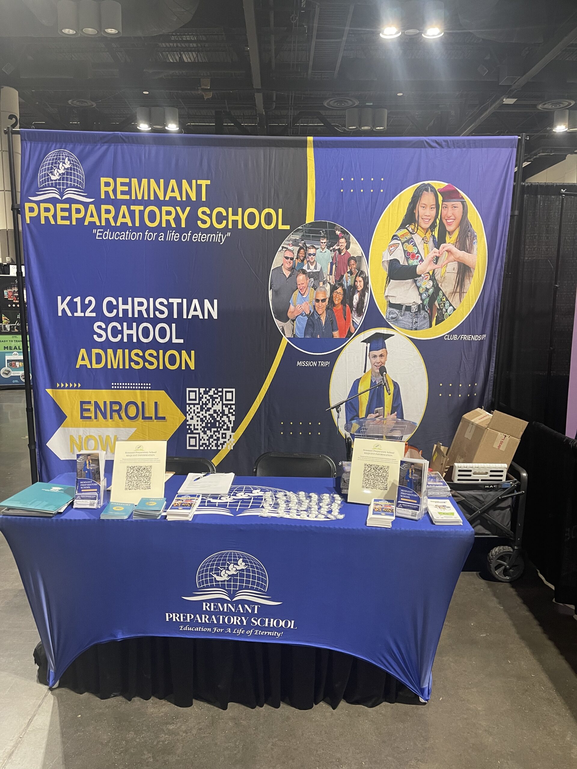 Booth for Remnant Preparatory School showcasing enrollment for K12 Christian education. Features promotional materials and images of school activities.